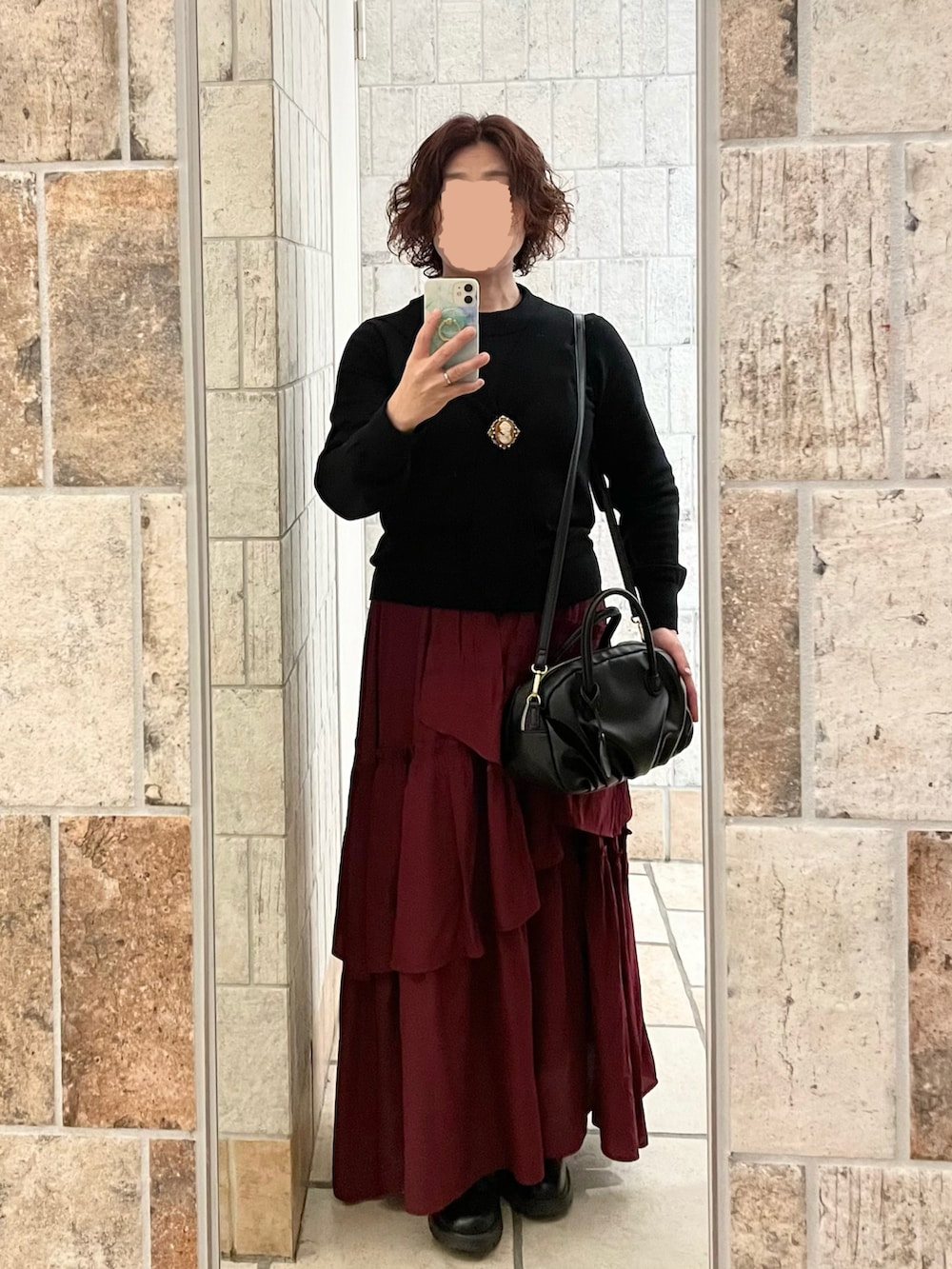 ブラック系のニット/セーター、レッド系のスカート、ブラック系のブーツを着用したレディースの冬コーディネートの2枚目の写真