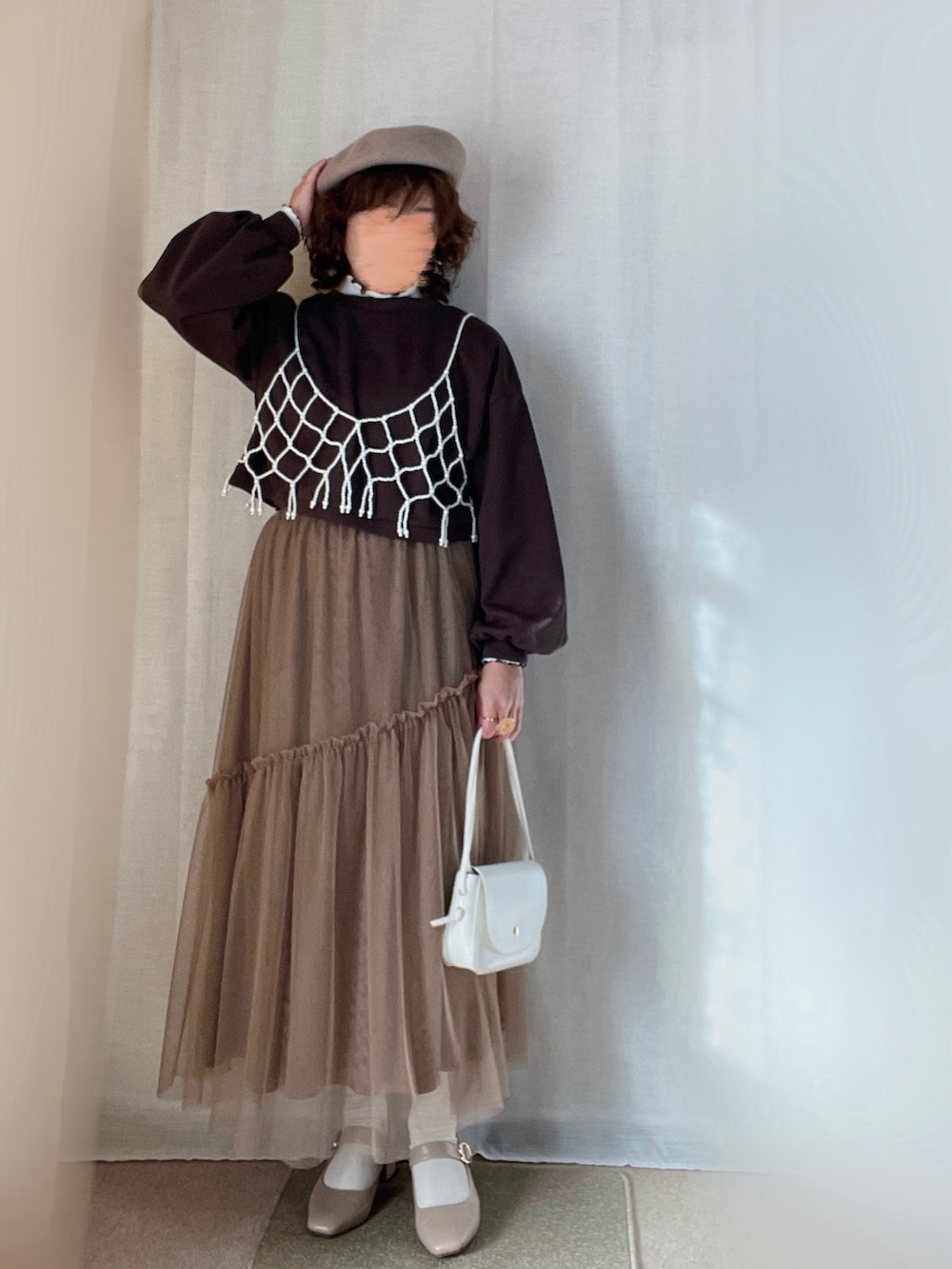 ホワイト系のキャミソール、ベージュ系のトレンチコート、ブラウン系のカーディガン/ボレロを着用したレディースの春コーディネートの2枚目の写真