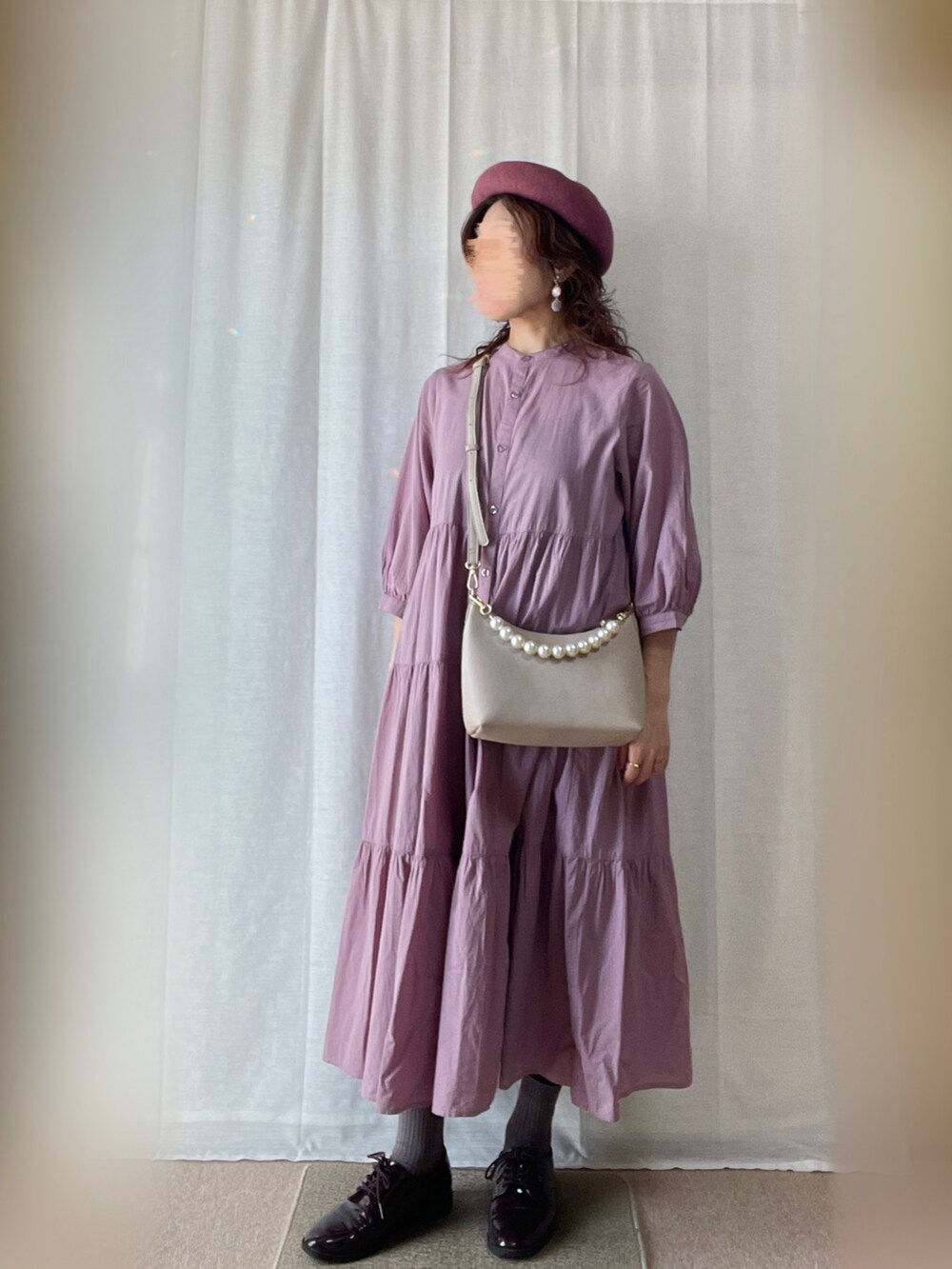 パープル系のワンピース、ベージュ系のベスト、パープル系のドレスシューズを着用したレディースの秋コーディネートの2枚目の写真