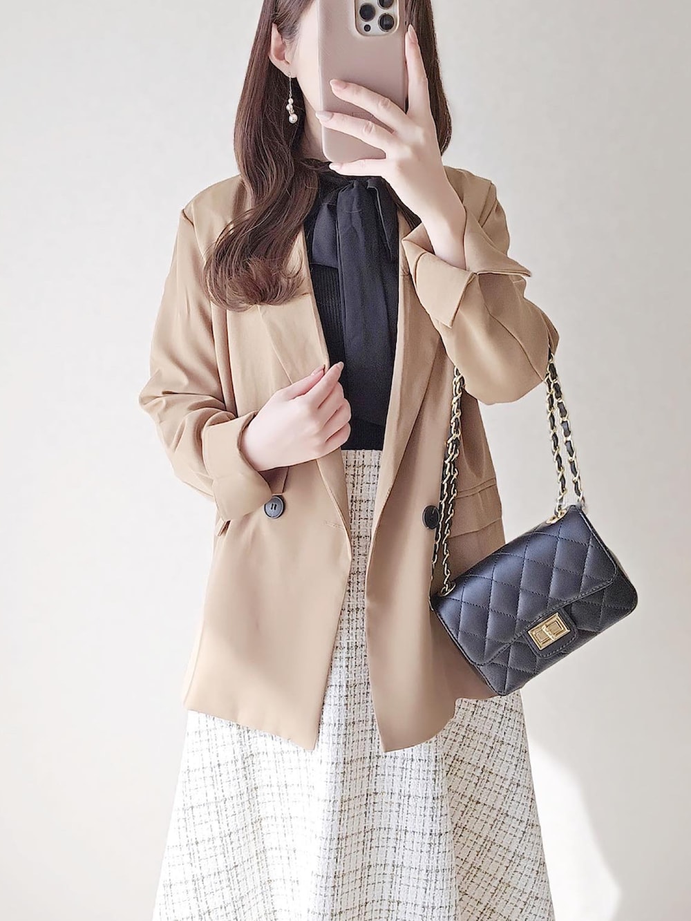 ブラウン系のテーラードジャケット、ホワイト系のスカート、ブラック系のショルダーバッグを着用したレディースの秋コーディネートの2枚目の写真