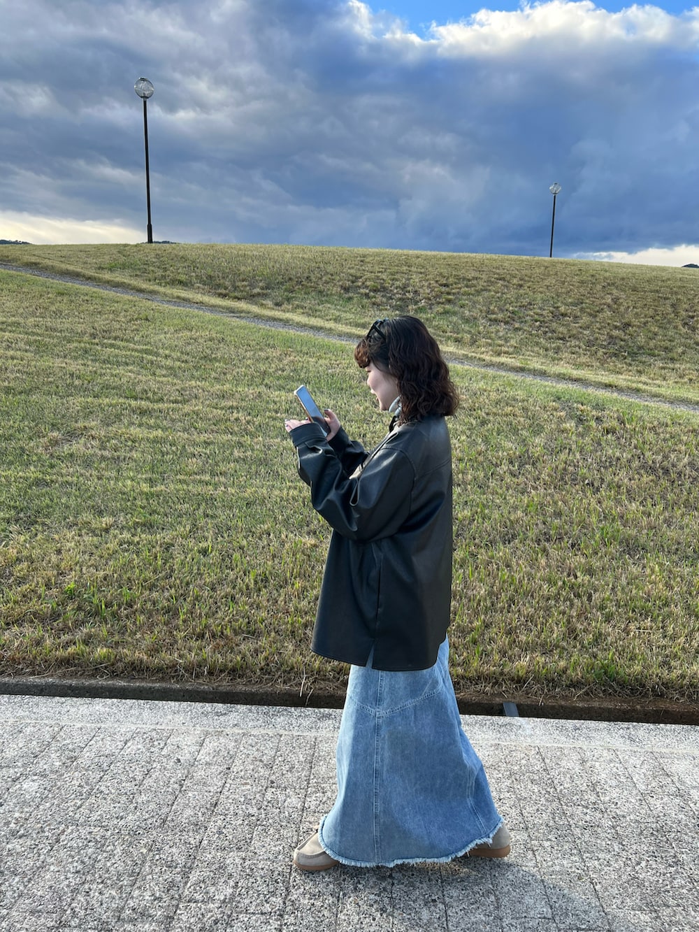 ブラック系のノーカラージャケット、ブルー系のデニムスカート、ベージュ系のモカシン/デッキシューズを着用したレディースの秋コーディネートの2枚目の写真