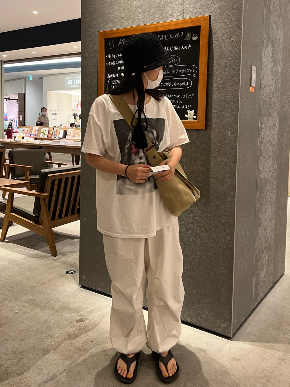 ブラック系のビーチサンダル、ホワイト系のカーゴパンツ、ベージュ系のメッセンジャーバッグを着用したレディースの夏コーディネートの2枚目の写真