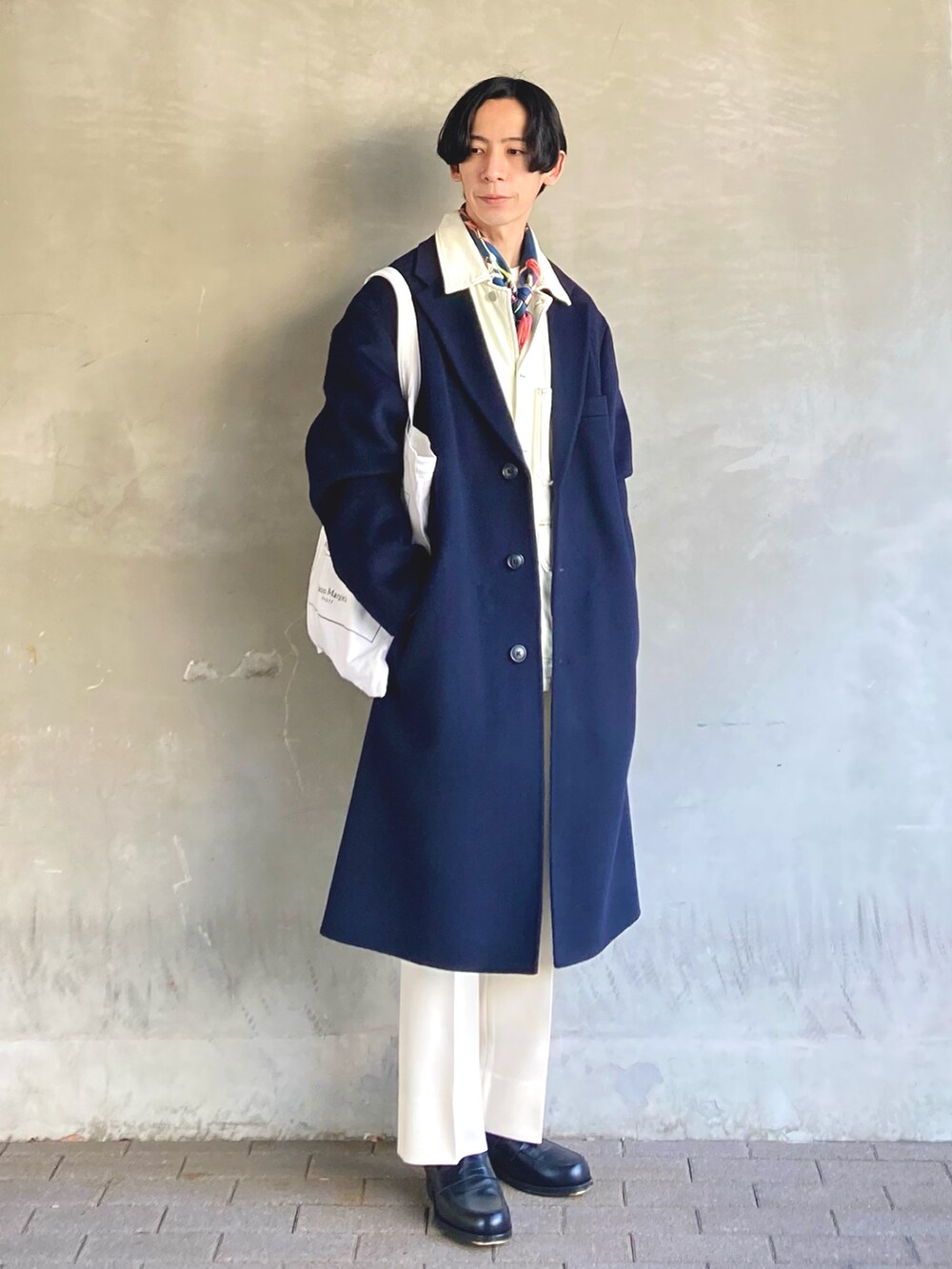 ブラック系のローファー、ホワイト系のトートバッグ、ホワイト系のスラックスを着用したメンズの冬コーディネートの2枚目の写真