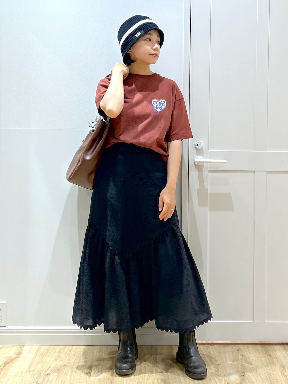 ブラウン系のTシャツ/カットソー、ブラック系のスカート、ブラウン系のトートバッグを着用したレディースの夏コーディネートの2枚目の写真