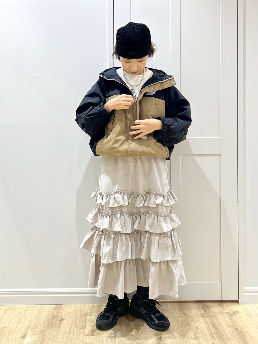 ベージュ系のマウンテンパーカー、ホワイト系のTシャツ/カットソー、ベージュ系のスカートを着用したレディースの秋コーディネートの7枚目の写真