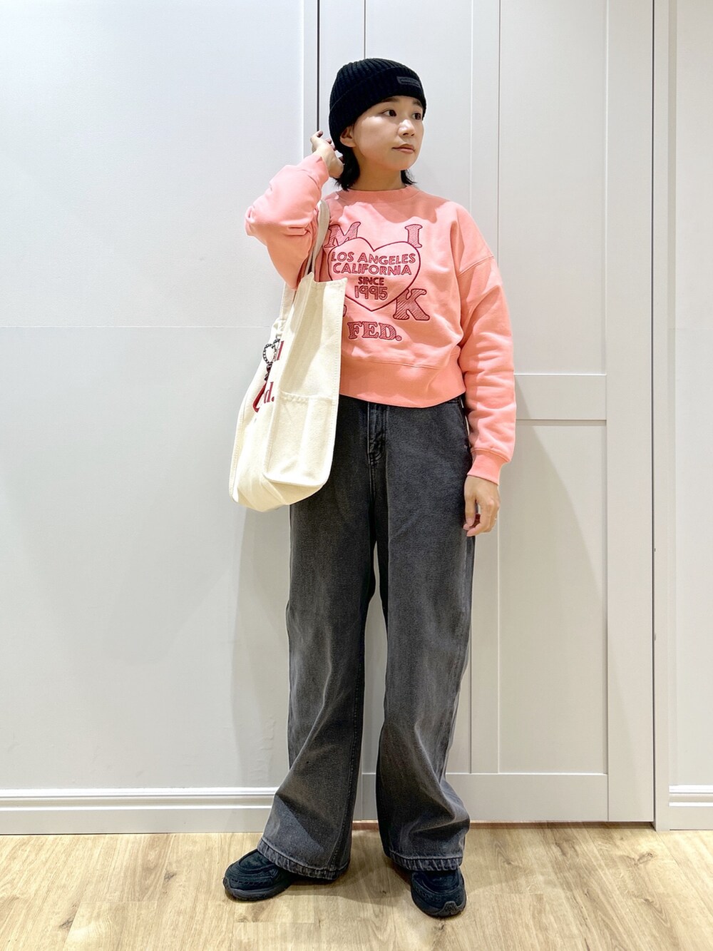 ピンク系のスウェット、ブラック系のデニムパンツ、レッド系のトートバッグを着用したレディースの冬コーディネートの3枚目の写真