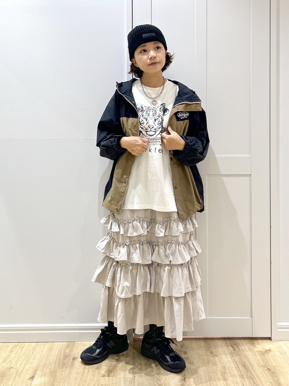 ベージュ系のマウンテンパーカー、ホワイト系のTシャツ/カットソー、ベージュ系のスカートを着用したレディースの秋コーディネートの5枚目の写真