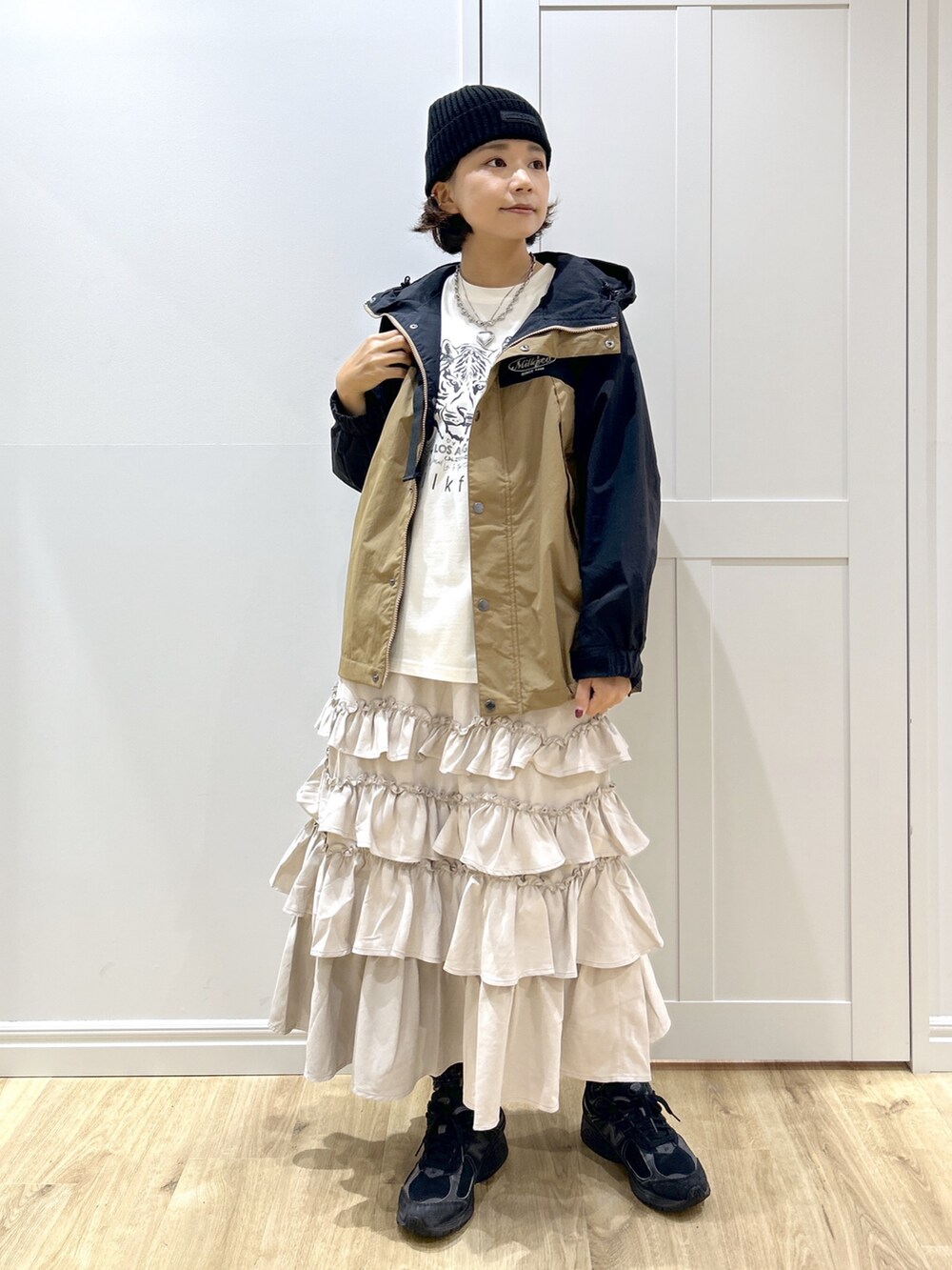 ベージュ系のマウンテンパーカー、ホワイト系のTシャツ/カットソー、ベージュ系のスカートを着用したレディースの秋コーディネートの2枚目の写真