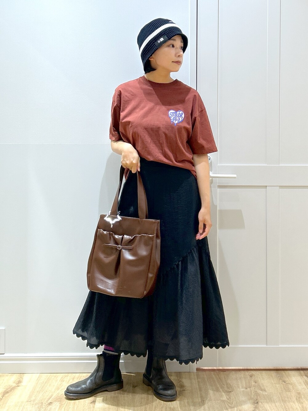 ブラウン系のTシャツ/カットソー、ブラック系のスカート、ブラウン系のトートバッグを着用したレディースの夏コーディネートの3枚目の写真