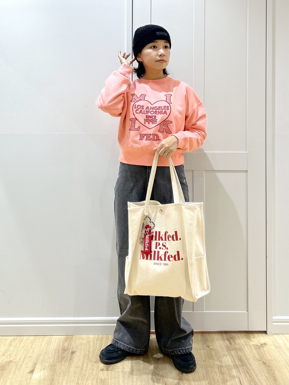 ピンク系のスウェット、ブラック系のデニムパンツ、レッド系のトートバッグを着用したレディースの冬コーディネートの2枚目の写真