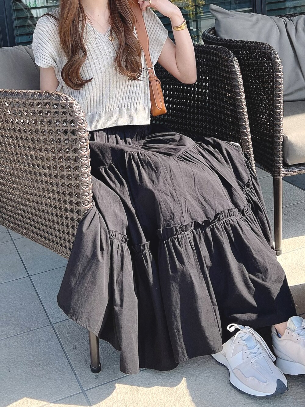 ブラック系のスカート、ベージュ系のスニーカー、ゴールド系のネックレスを着用したレディースの春コーディネートの3枚目の写真