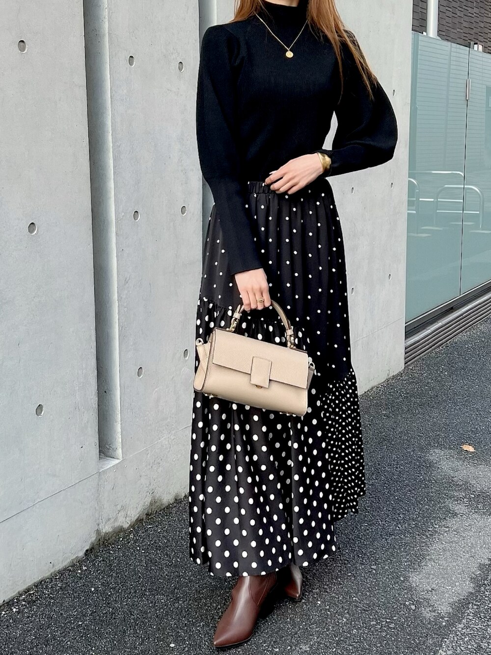 ブラック系のスカート、ブラック系のニット/セーター、ベージュ系のショルダーバッグを着用したレディースの秋コーディネートの2枚目の写真