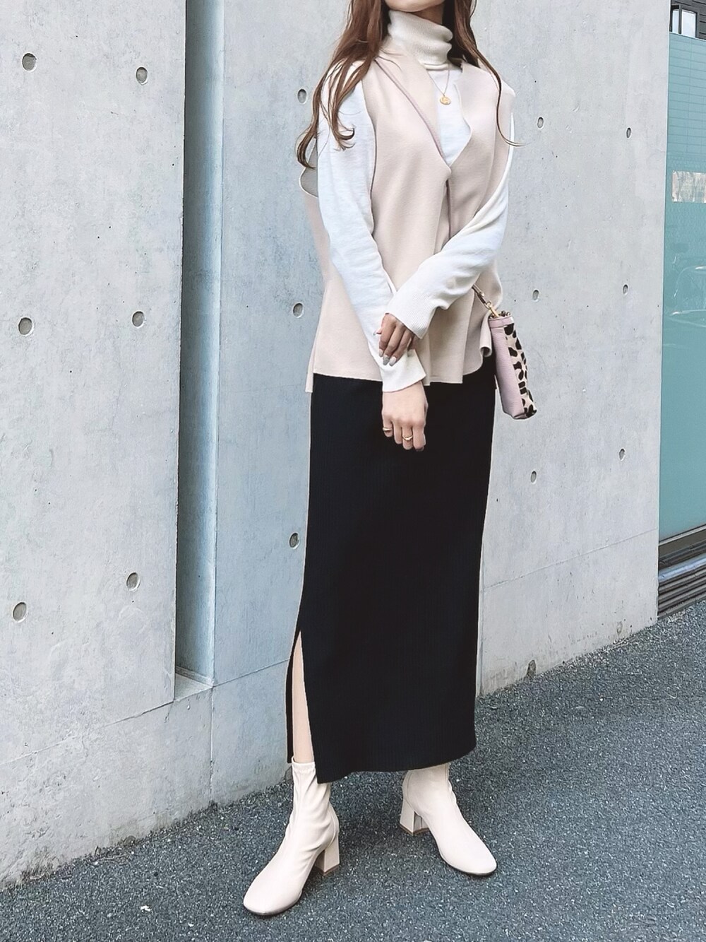 ブラック系のスカート、ホワイト系のブーツ、その他のバッグを着用したレディースの冬コーディネートの2枚目の写真