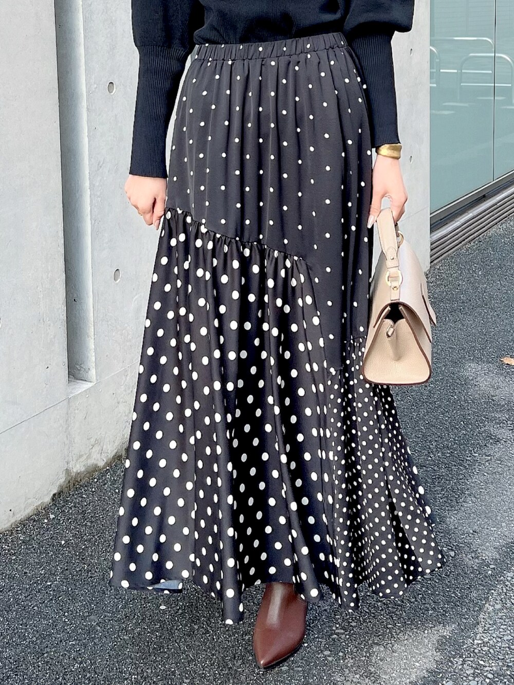 ブラック系のスカート、ブラック系のニット/セーター、ベージュ系のショルダーバッグを着用したレディースの秋コーディネートの3枚目の写真