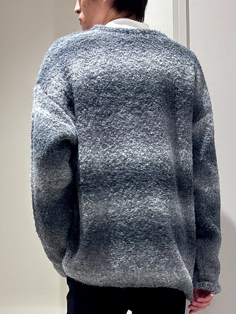 ブラック系のニット/セーター、ホワイト系のTシャツ/カットソー、ブラック系のチノパンツを着用したメンズの秋コーディネートの3枚目の写真