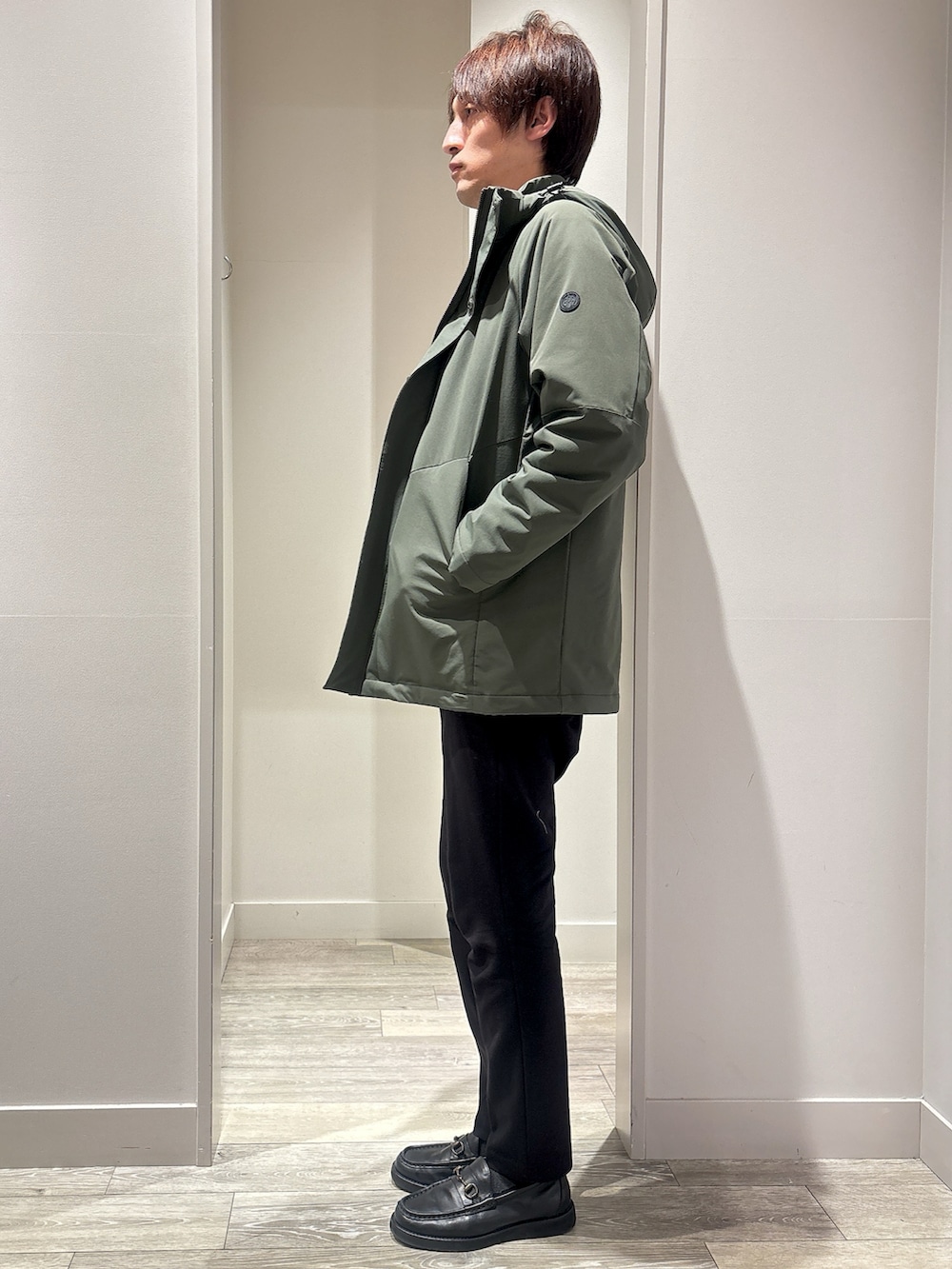 グリーン系のブルゾン、ブラック系のスラックス、グレー系のニット/セーターを着用したメンズの春コーディネートの2枚目の写真