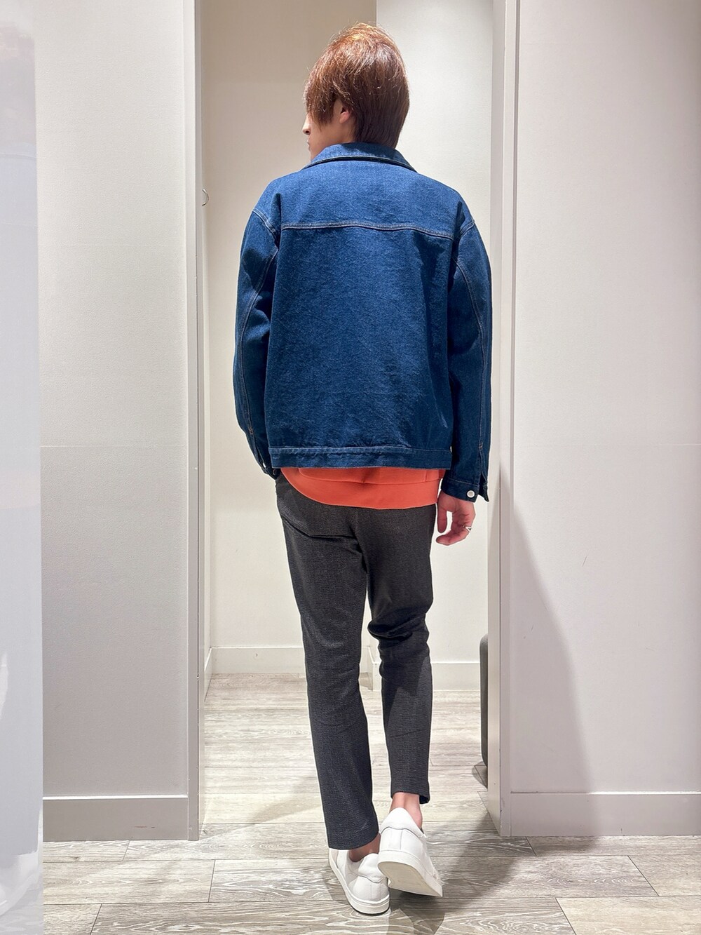 オレンジ系のスウェット、ブルー系のデニムジャケット、ブラック系のスラックスを着用したメンズの秋コーディネートの3枚目の写真