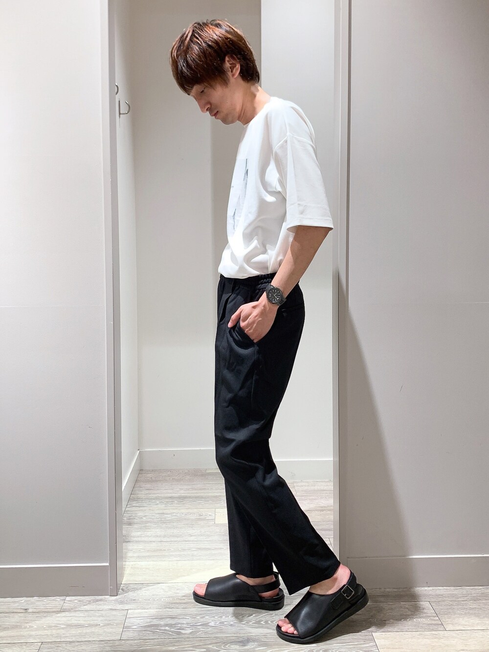 ホワイト系のTシャツ/カットソー、ブラック系のスラックス、ブラック系のサンダルを着用したメンズの春コーディネートの2枚目の写真