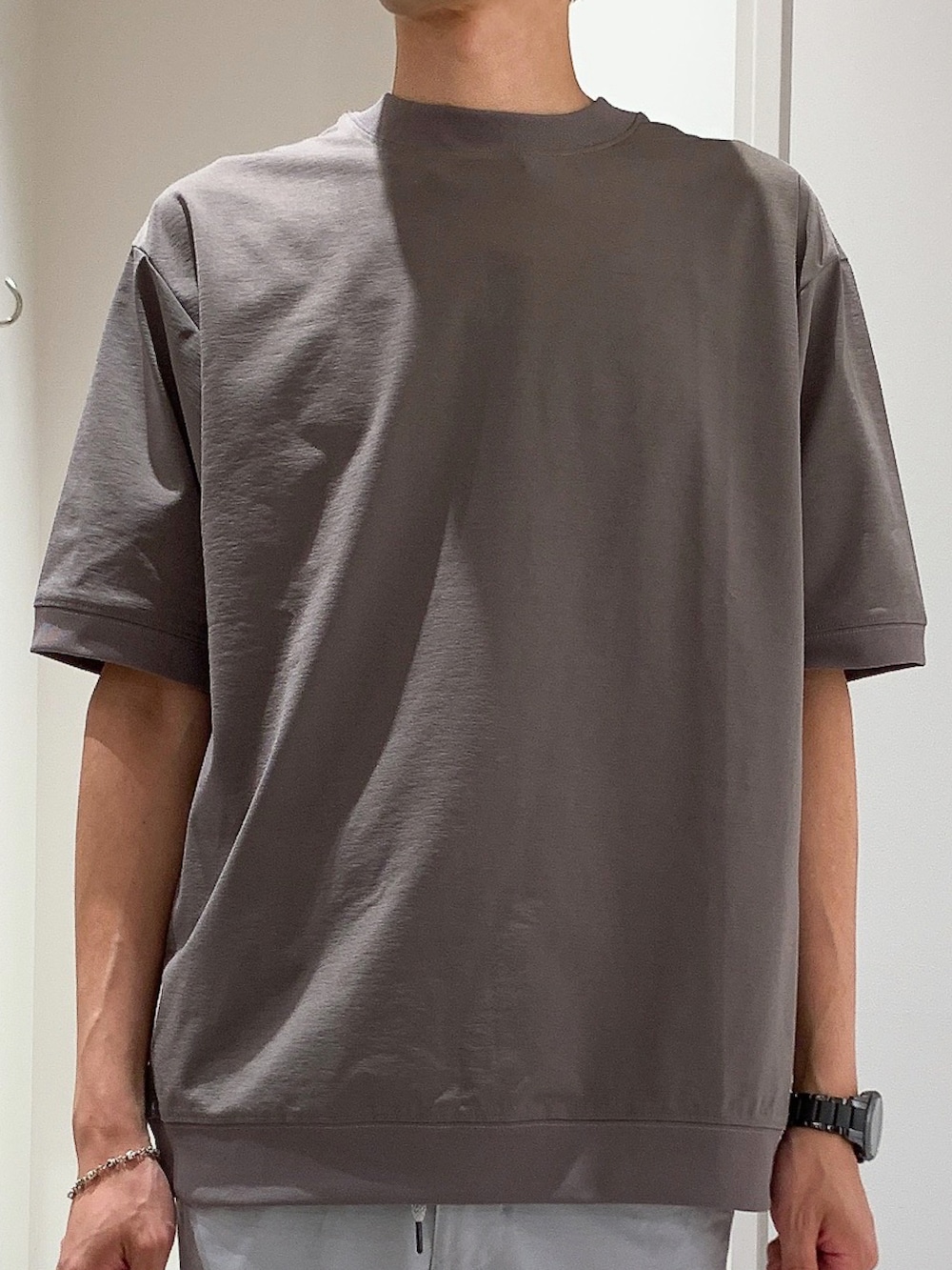 ブラウン系のTシャツ/カットソー、ブラック系のボディバッグ/ウエストポーチ、グレー系のスラックスを着用したメンズの夏コーディネートの4枚目の写真