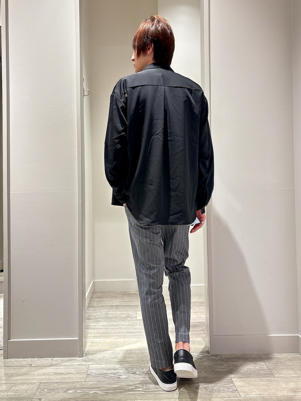 ブラック系のシャツ/ブラウス、グレー系のスラックス、ホワイト系のTシャツ/カットソーを着用したメンズの春コーディネートの3枚目の写真