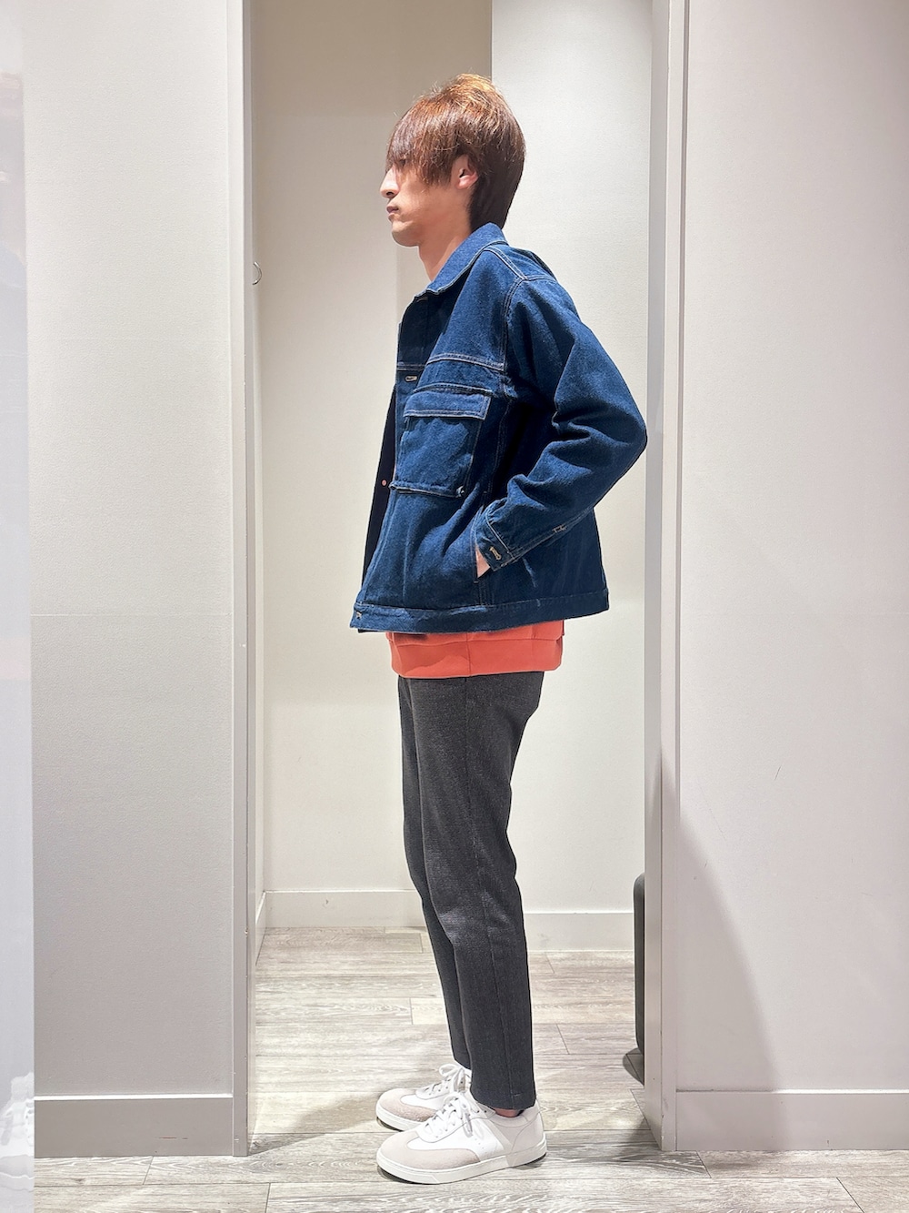 オレンジ系のスウェット、ブルー系のデニムジャケット、ブラック系のスラックスを着用したメンズの秋コーディネートの2枚目の写真