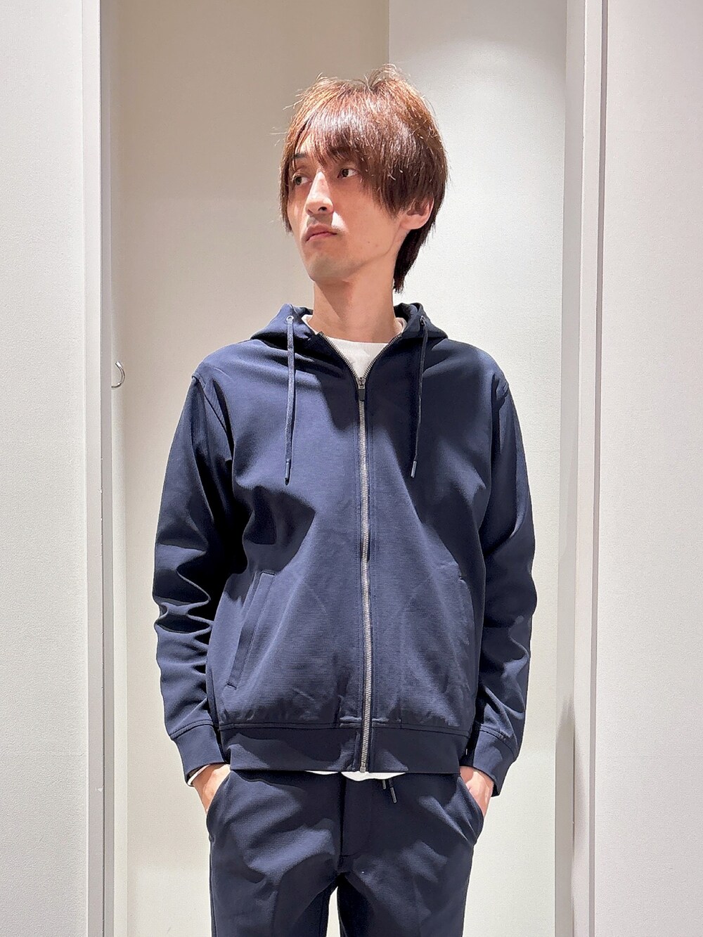 ブルー系のパーカー、ホワイト系のTシャツ/カットソー、ブルー系のスラックスを着用したメンズの秋コーディネートの5枚目の写真