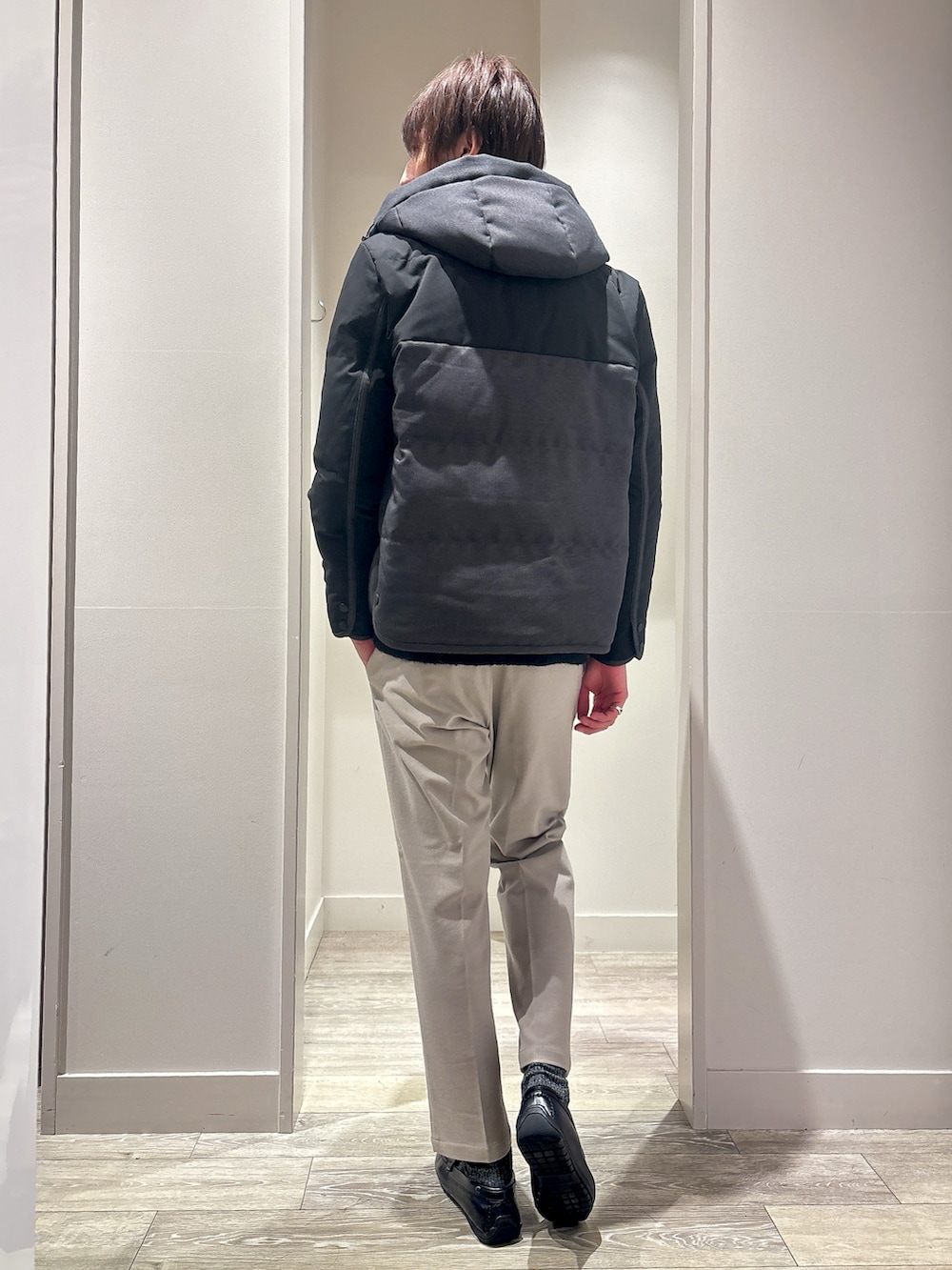 グレー系のダウンジャケット/コート、グレー系のニット/セーター、ベージュ系のスラックスを着用したメンズの冬コーディネートの3枚目の写真