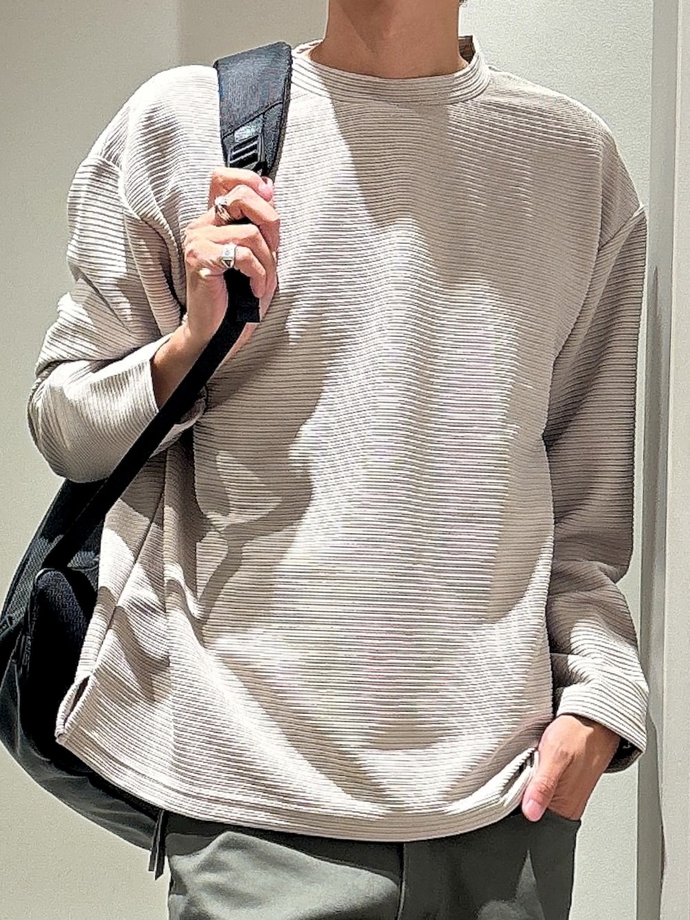 ベージュ系のTシャツ/カットソー、ブラック系のバックパック/リュック、グリーン系のチノパンツを着用したメンズの秋コーディネートの4枚目の写真