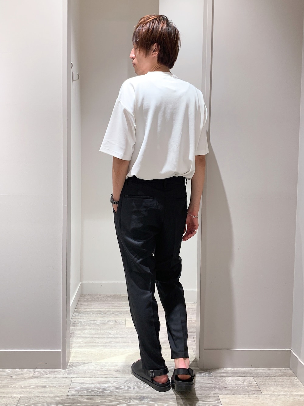 ホワイト系のTシャツ/カットソー、ブラック系のスラックス、ブラック系のサンダルを着用したメンズの春コーディネートの3枚目の写真