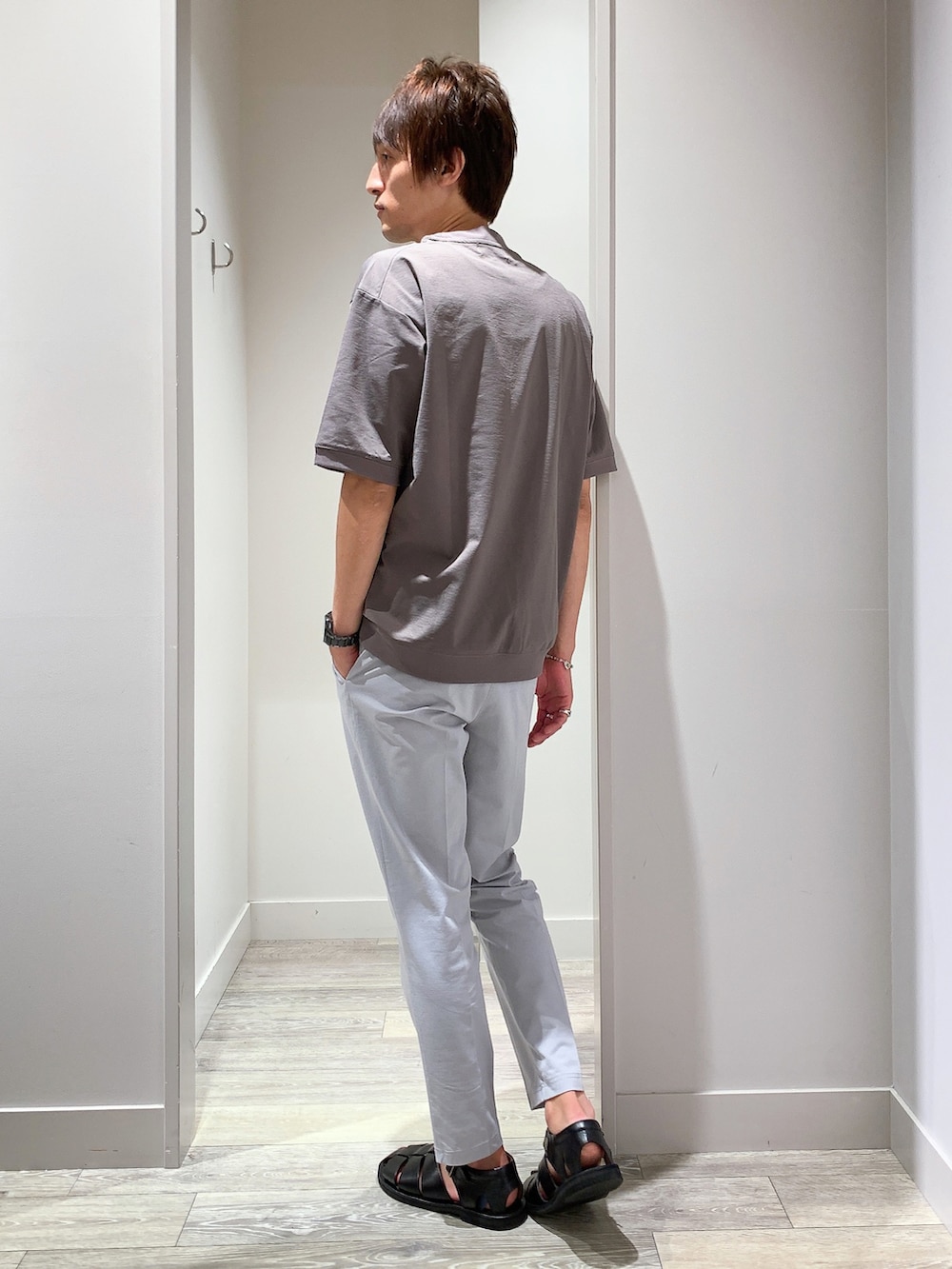 ブラウン系のTシャツ/カットソー、ブラック系のボディバッグ/ウエストポーチ、グレー系のスラックスを着用したメンズの夏コーディネートの3枚目の写真