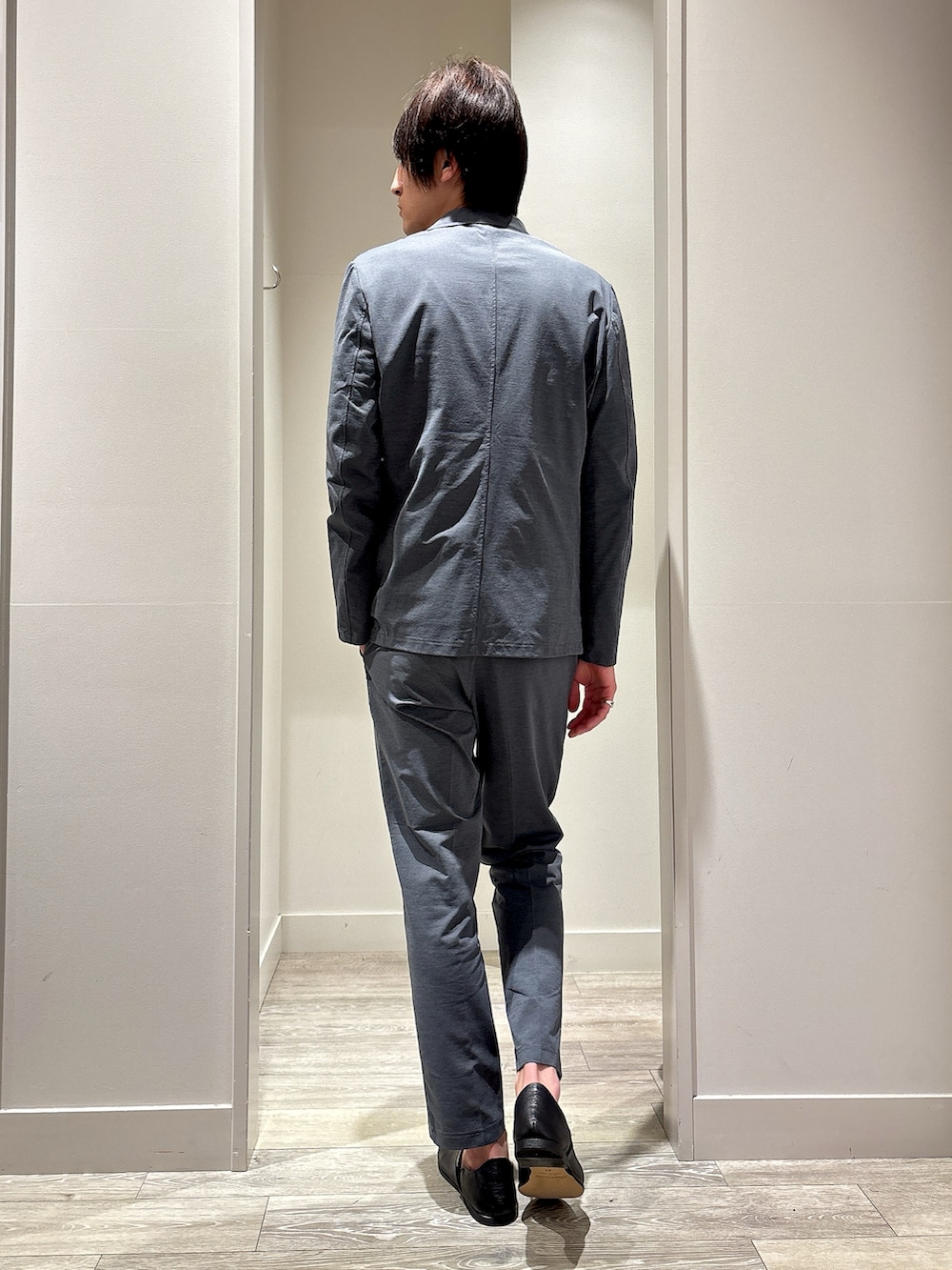 グレー系のセットアップ、グレー系のテーラードジャケット、ブラック系のTシャツ/カットソーを着用したメンズの春コーディネートの3枚目の写真