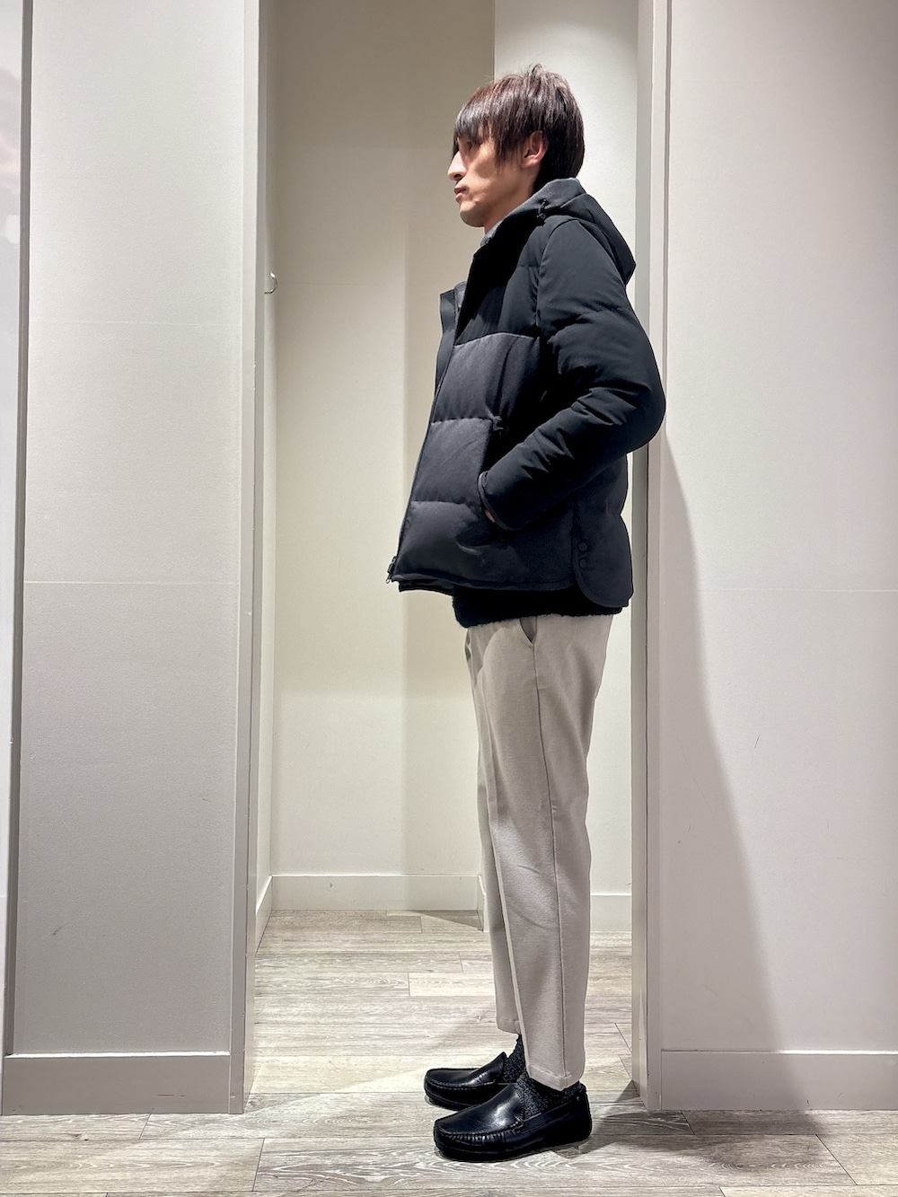 グレー系のダウンジャケット/コート、グレー系のニット/セーター、ベージュ系のスラックスを着用したメンズの冬コーディネートの2枚目の写真