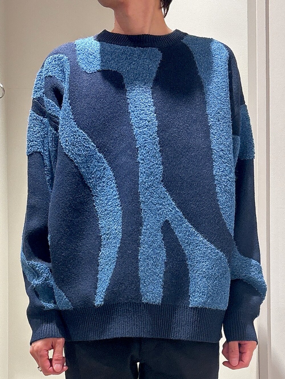 ブルー系のニット/セーター、ブラック系のチノパンツ、ブラック系のブーツを着用したメンズの冬コーディネートの3枚目の写真