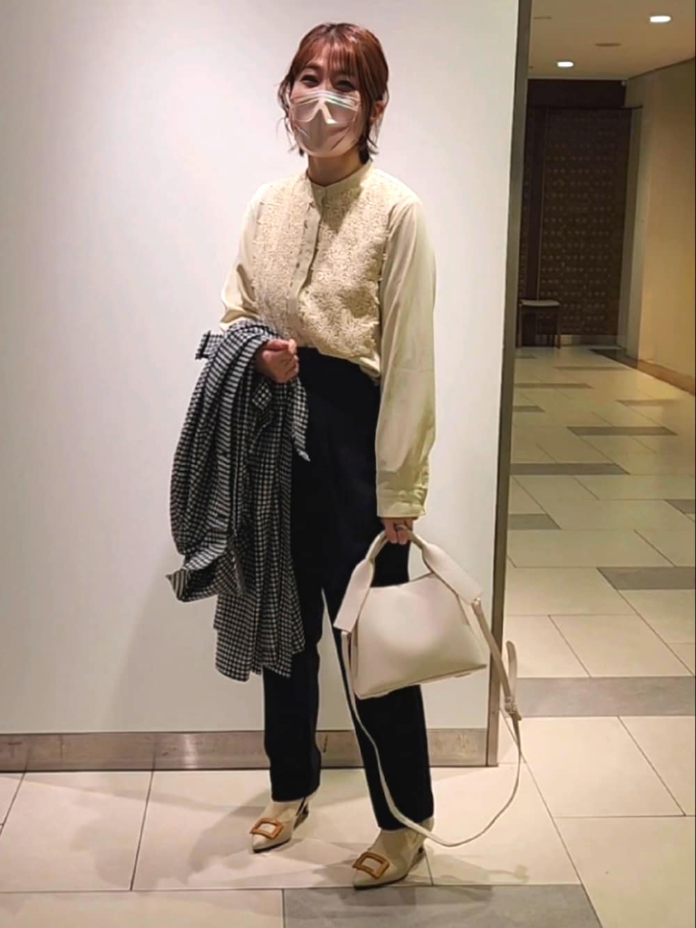 ブラック系のステンカラーコート、イエロー系のシャツ/ブラウス、ブラック系のその他パンツを着用したレディースの冬コーディネートの2枚目の写真