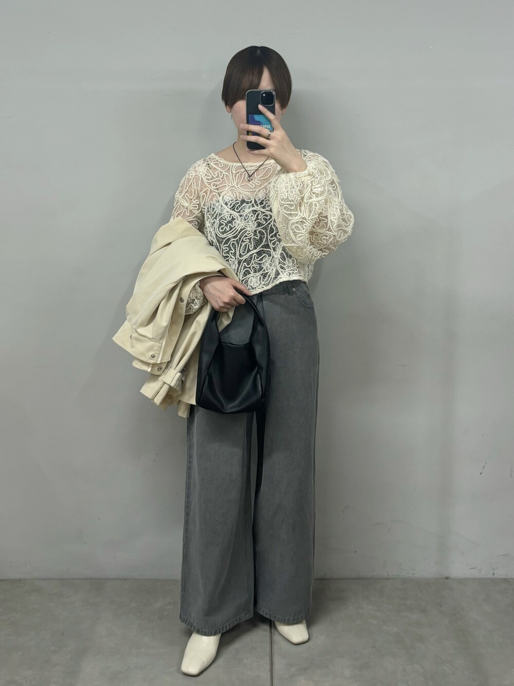 ブラック系のショルダーバッグ、ホワイト系のトレンチコート、グレー系のデニムパンツを着用したレディースの春コーディネートの2枚目の写真