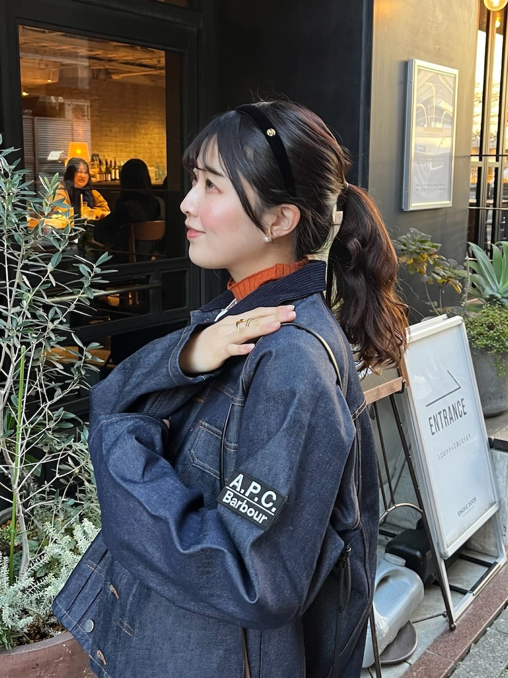 オレンジ系のニット/セーター、ブルー系のデニムジャケット、ベージュ系のチノパンツを着用したレディースの冬コーディネートの2枚目の写真