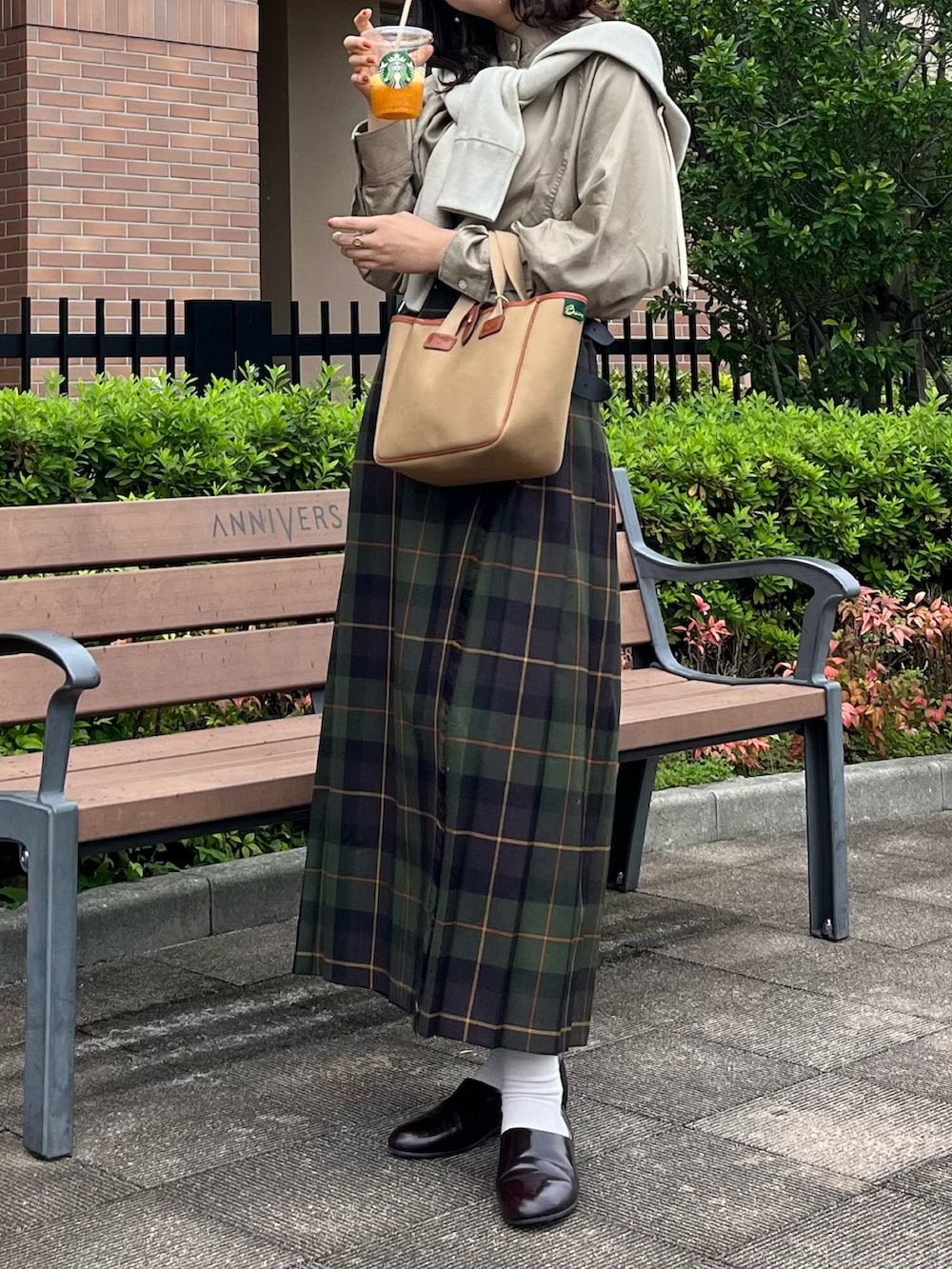 ブラウン系のドレスシューズ、グリーン系のスカート、グリーン系のトートバッグを着用したレディースの秋コーディネートの2枚目の写真