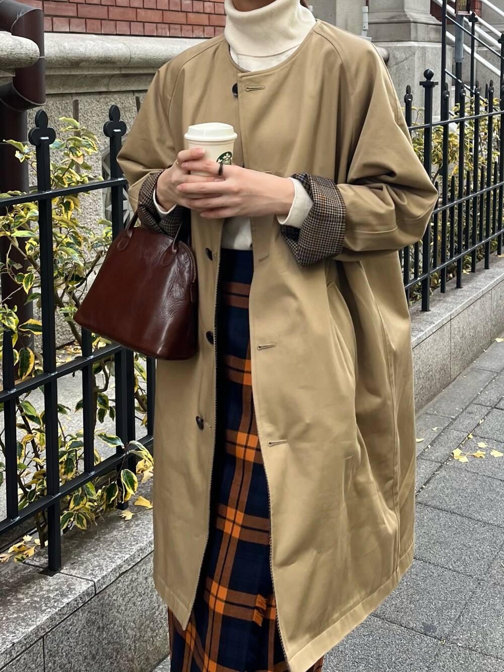 ブラウン系のハンドバッグ、ベージュ系のモカシン/デッキシューズ、ベージュ系のノーカラーコートを着用したレディースの冬コーディネートの3枚目の写真