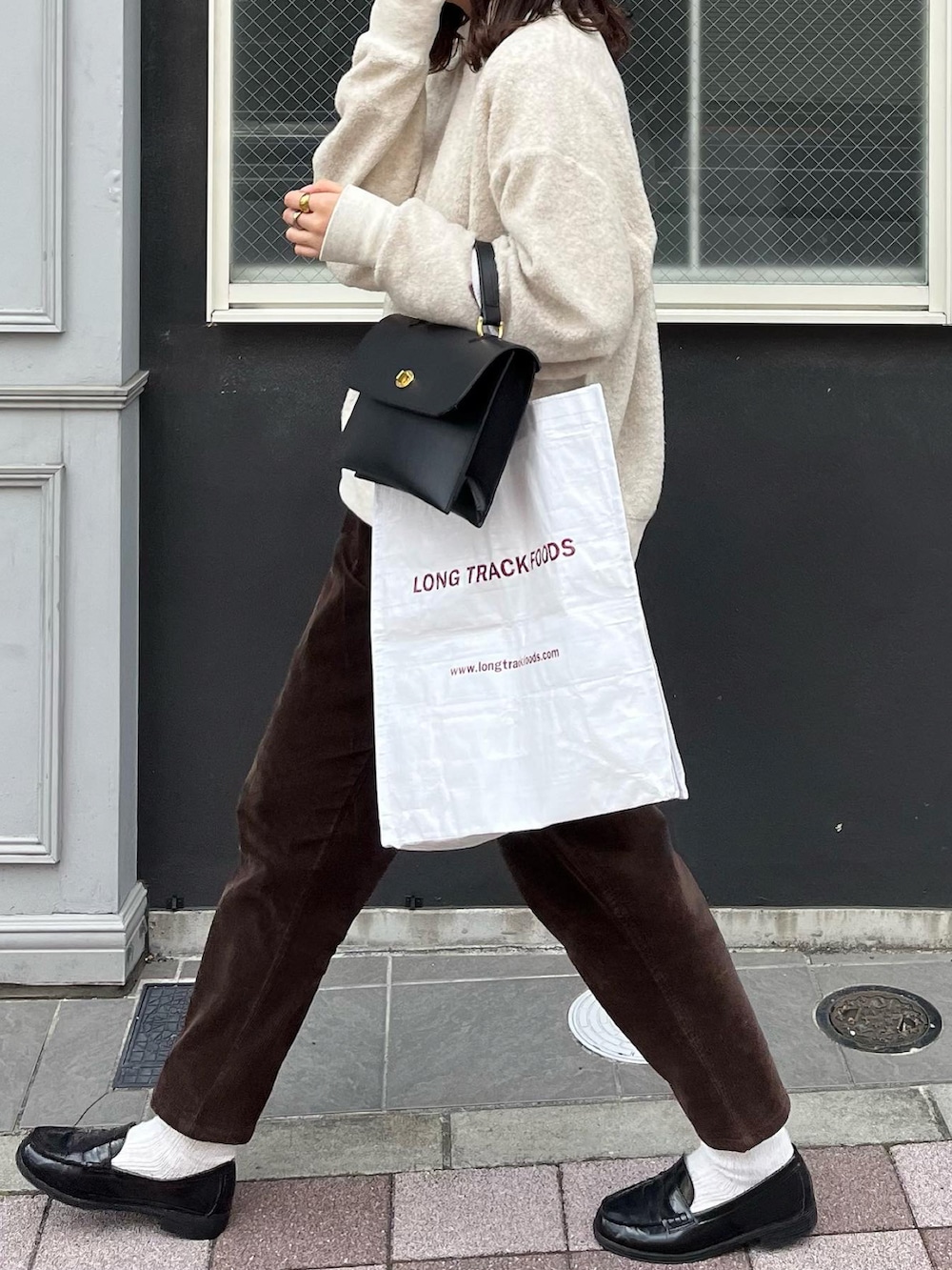 ブラック系のショルダーバッグ、ベージュ系のスウェット、ブラウン系のパンツを着用したレディースの秋コーディネートの2枚目の写真