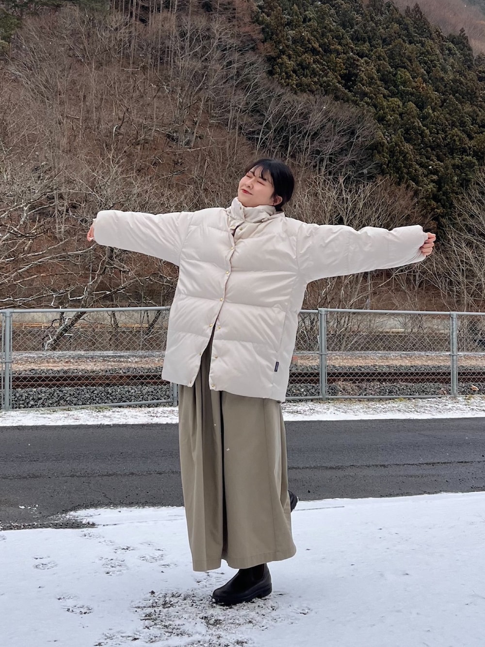 ホワイト系のダウンジャケット/コート、ベージュ系のスカート、ブラウン系のブーツを着用したレディースの冬コーディネートの2枚目の写真