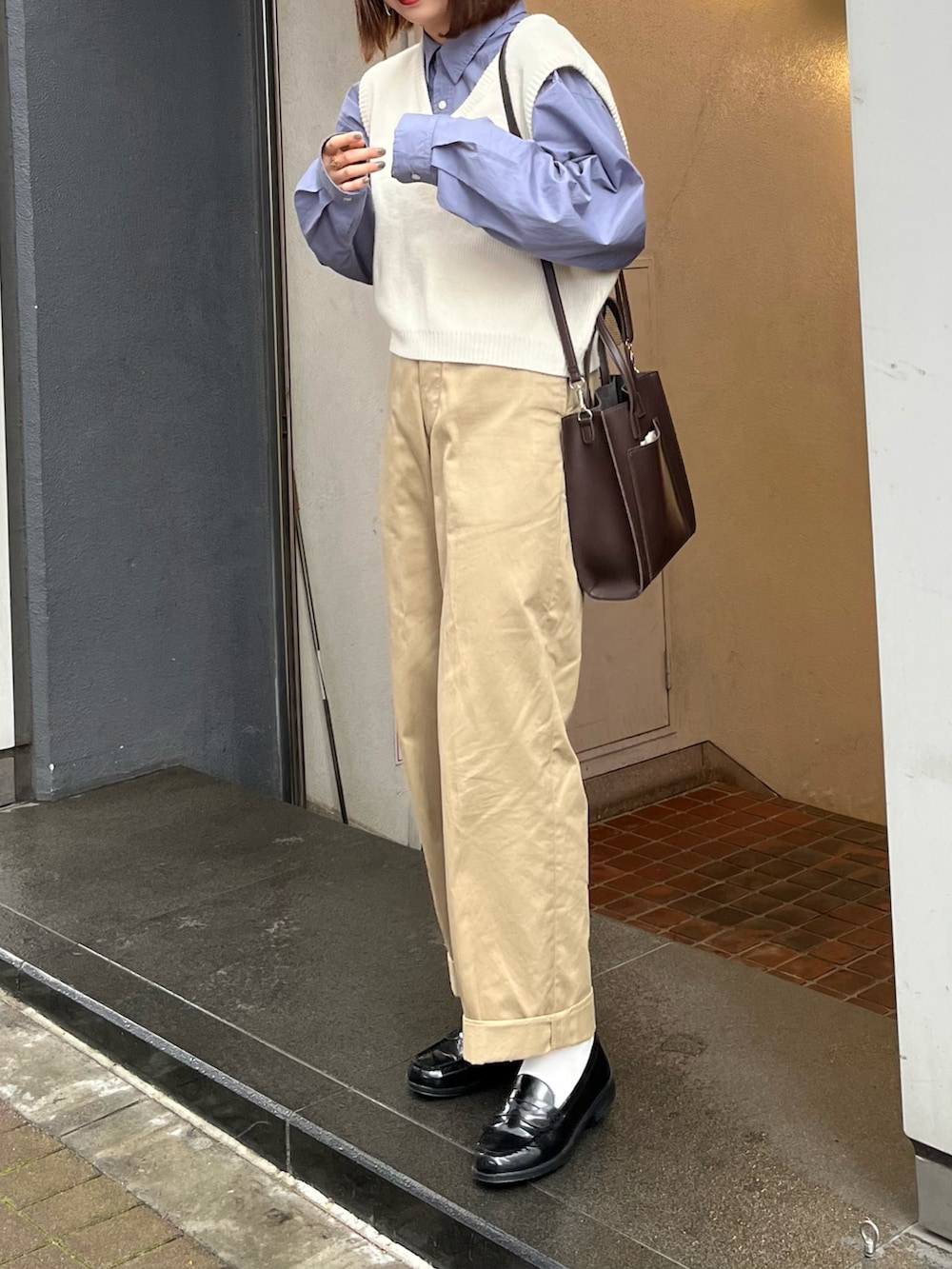 ブラウン系のショルダーバッグ、ブルー系のシャツ/ブラウス、ブラック系のチノパンツを着用したレディースの春コーディネートの2枚目の写真