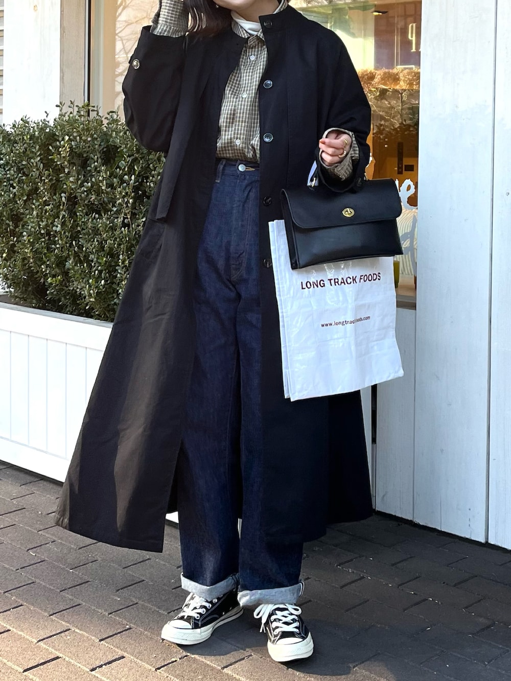 ブラック系のスニーカー、ブラック系のショルダーバッグ、ブルー系のデニムパンツを着用したレディースの冬コーディネートの2枚目の写真