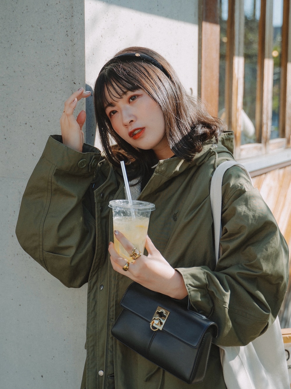 グリーン系のモッズコート、ブラック系のショルダーバッグ、ブラック系のワンピース/ドレスを着用したレディースの秋コーディネートの2枚目の写真