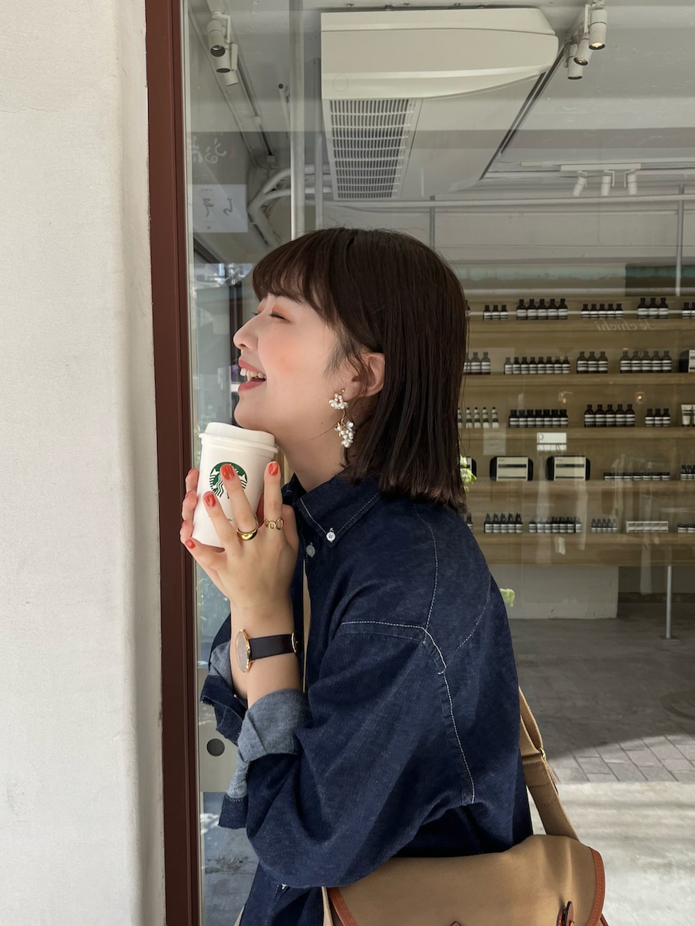 ベージュ系のスカート、グリーン系のショルダーバッグ、ブルー系のシャツ/ブラウスを着用したレディースの秋コーディネートの2枚目の写真