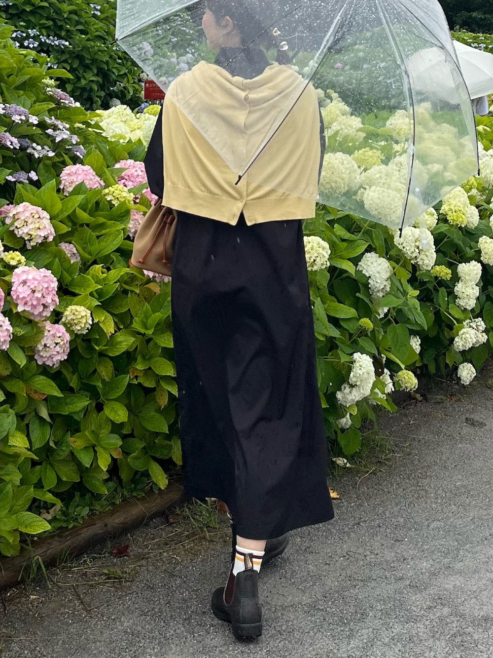 グリーン系のショルダーバッグ、ブラウン系のブーツ、ブラック系のワンピース/ドレスを着用したレディースの夏コーディネートの3枚目の写真