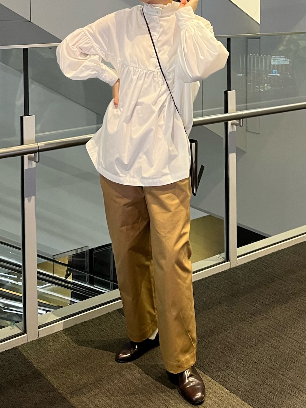 ブラウン系のショルダーバッグ、ホワイト系のシャツ/ブラウス、ベージュ系のチノパンツを着用したレディースの秋コーディネートの2枚目の写真