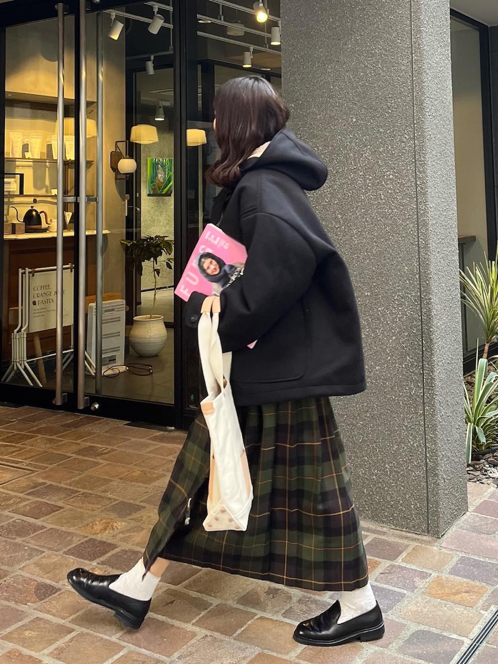 ベージュ系のトートバッグ、ブラック系のジャケット/アウター、グリーン系のスカートを着用したレディースの冬コーディネートの2枚目の写真