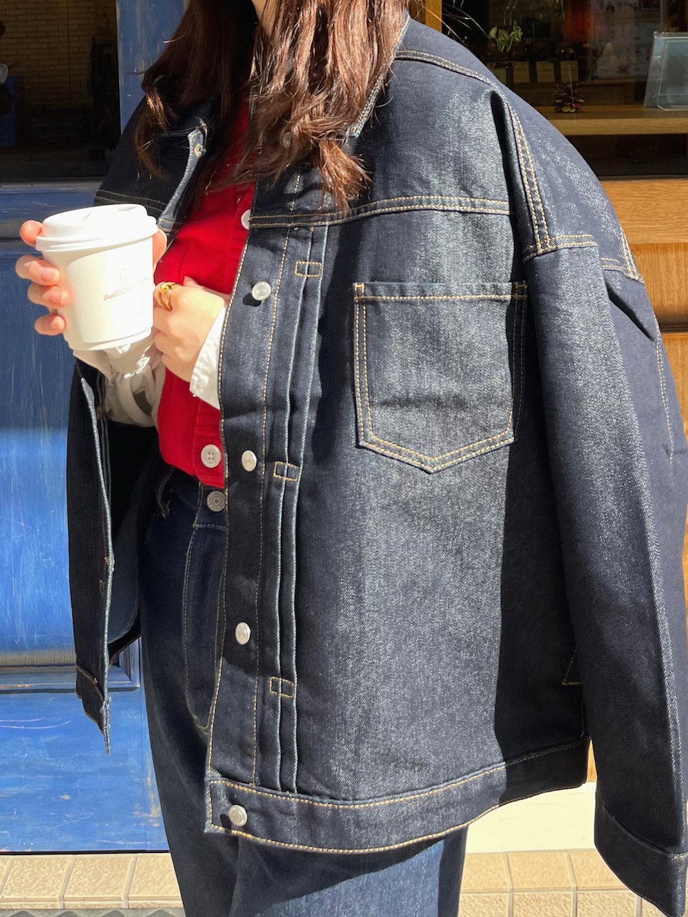 ブルー系のデニムパンツ、ブラック系のショルダーバッグ、ブルー系のデニムジャケットを着用したレディースの冬コーディネートの4枚目の写真