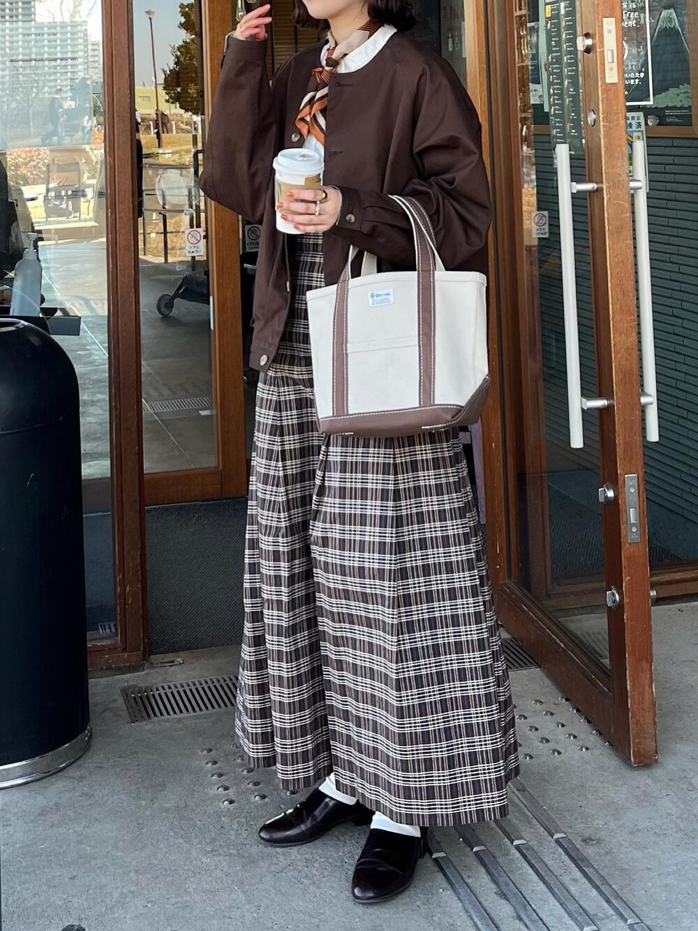 ブラウン系のスカート、ブラウン系のトートバッグ、ブラウン系のドレスシューズを着用したレディースの冬コーディネートの2枚目の写真