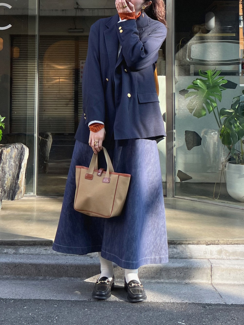 グリーン系のトートバッグ、ブルー系のスカート、ブラック系のローファーを着用したレディースの冬コーディネートの2枚目の写真